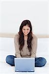 Smiling woman with legs crossed as she watches her laptop.