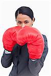 Close up of belligerent saleswoman with boxing gloves against a white background