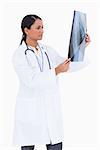 Side view of female physician checking x-ray against a white background