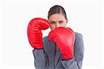 Tradeswoman with boxing gloves in defensive position against a white background