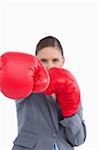 Attacking fist of tradeswoman in boxing glove against a white background