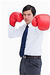 Attacking fist of tradesman in boxing glove against a white background