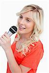 Smiling woman singing with a microphone against a white background