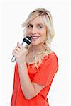 Young attractive and blonde woman smiling while singing in a cordless microphone