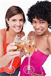 Two glasses of white wine being clinked by young women