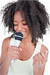 Young woman singing karaoke with a microphone against a white background