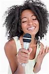 Concentrated young woman singing into a microphone against a white background