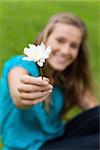 Beautiful white flower held by a smiling young girl in a park