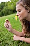 Young relaxed girl closing her eyes while smelling a yellow flower in a park