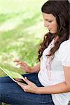 Young attractive woman sitting in a public garden while using her tablet computer