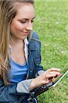 Young peaceful woman touching her tablet computer while sitting in the countryside