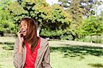 Cheerful woman laughing on the phone in an open grassland area