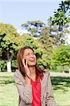 Woman laughing on the phone while looking into the sky with the sun shining on her face