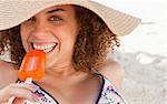 Young woman looking at the camera while eating a delicious ice cream on the beach