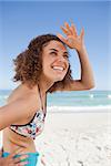 Happy young woman placing her hand on her forehead to protect from the sunlight