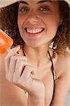 Young woman showing a beaming smile while holding an orange popsicle