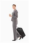 A businesswoman is walking with coffee and suitcase