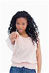 A girl is pointing straight at the camera against a white background