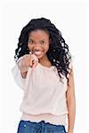 A smiling woman is pointing her finger at the camera against a white background