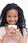 A young woman is holding a cup of coffee wiht her both hands