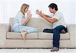 A young couple sitting on a couch are having an argument