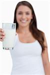 Glass of milk being held by a young woman against a white background