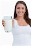 Glass of milk being held by a young brunette woman against a white background