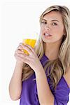 Attractive blonde woman holding an orange juice against a white background