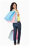 Rear view of a beautiful Latin student with shopping bags against white background