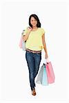Beautiful Latin student walking with shopping bags against white background
