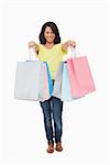 Beautiful Latin student showing her shopping bags against white background