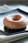 Fresh glazed doughnut on square black plate