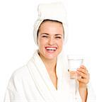 Smiling young woman in bathrobe with glass of water