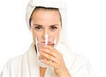 Young woman in bathrobe drinking pure water