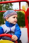 little boy playing on playground in toy car