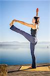 An image of a pretty woman doing yoga at the lake - Utthita Hasta Padangusthasana