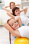 Kids exercising with their mother using gymnastic balls