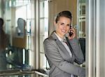 Smiling business woman talking cell phone in elevator