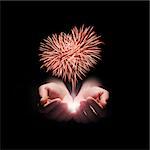 fireworks in the men's hands in the shape of a red heart on black background