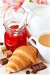 Fresh croissant with jam and cup of coffee for breakfast.