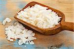 flakes of shredded coconut on a rustic wooden scoop