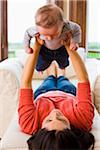 Woman Lying Down and Holding Her Three Month Old Son Up in Air