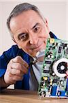 Portrait of Man Looking at Circuit Board with Magnifying Glass in Studio