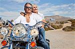 Senior couple on desert road sitting on motorcycle