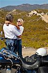 Senior couple embrace next to motorcycle in the desert