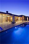 Rear view of luxury villa at night time with swimming pool