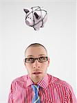 Young businessman looking up at piggy bank tied with rope representing trapped finances