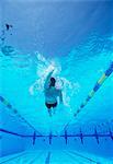 Underwater shot of young male athlete doing backstroke in swimming pool