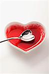 An empty heart-shaped bowl with a heart-shaped spoon