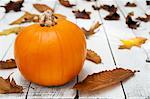 A pumpkin and autumnal leave on a wooden table